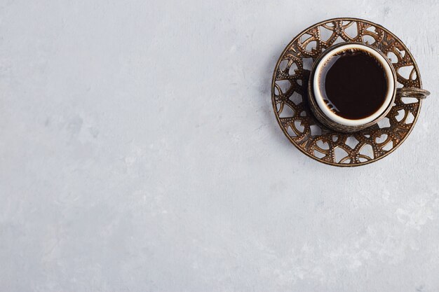 A cup of espresso in metallic saucer. 