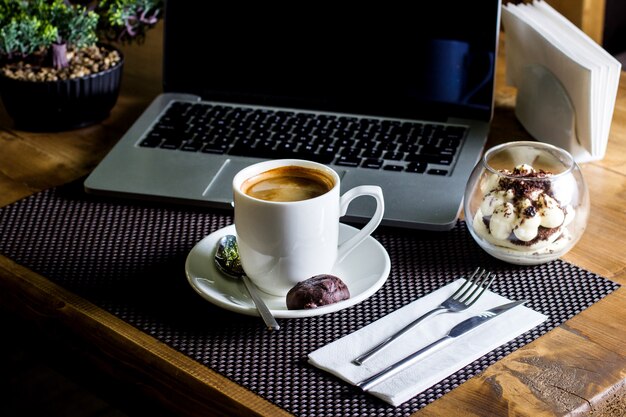 A cup of espresso served with tiramisu in glass bowl