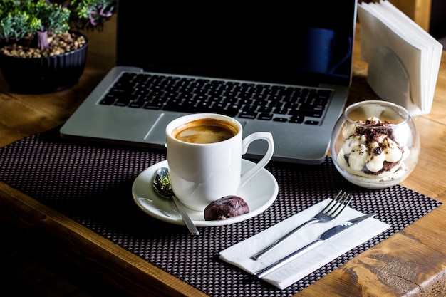 A cup of espresso served with tiramisu in glass bowl