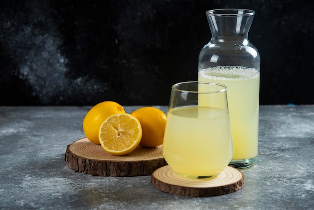 Free photo a cup of fresh lemon juice on wooden board.