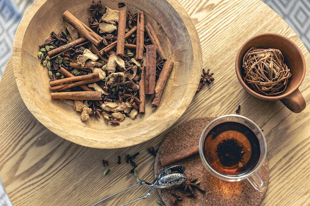 Cup of freshly brewed black tea different types of spices on wooden table