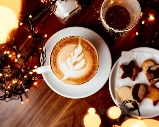 Free photo cup of hot cappuccino and a plate with cookies top view