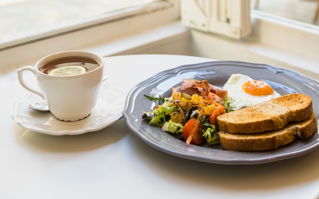 Free Photo cup of lemon tea and breakfast on round white table