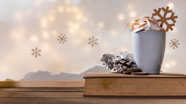 Free photo cup, snag and book on wood table near bank of snow, snowflakes and fairy lights