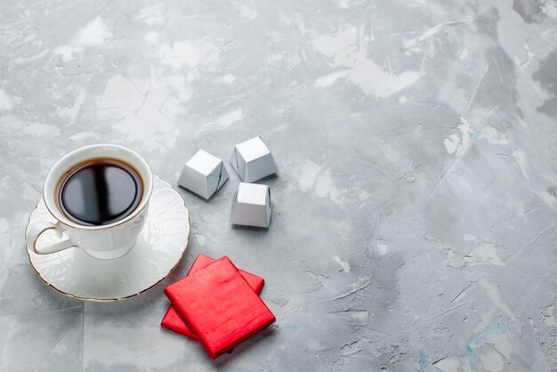 cup of tea hot inside white cup on glass plate with silver package chocolate candies on light desk, tea drink sweet chocolate cookie teatime