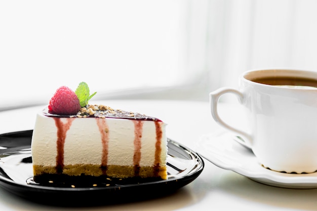 Cup of tea near the homemade cheesecake with fresh berries and mint for dessert on table