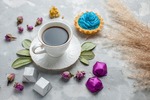 cup of tea with blue cream cake chocolate candies on white-grey,  biscuit sweet tea candy