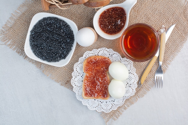 Cup of tea with breads and eggs on sackcloth.