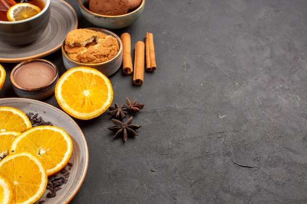 Free Photo cup of tea with cookies and fresh sliced oranges on dark