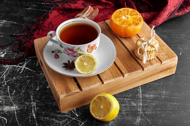 A cup of tea with fruits and cookies. 