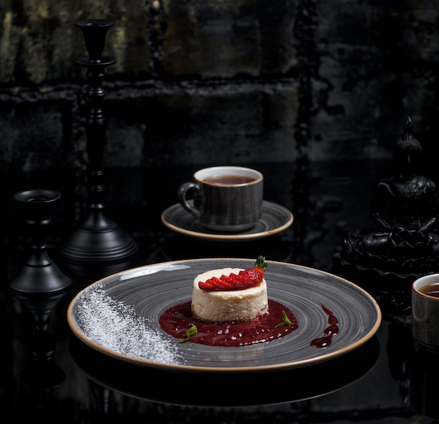 Free photo a cup of tea with ny cheesecake with berry sauce