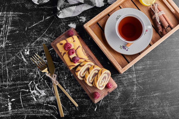 A cup of tea with roll cake, top view. 