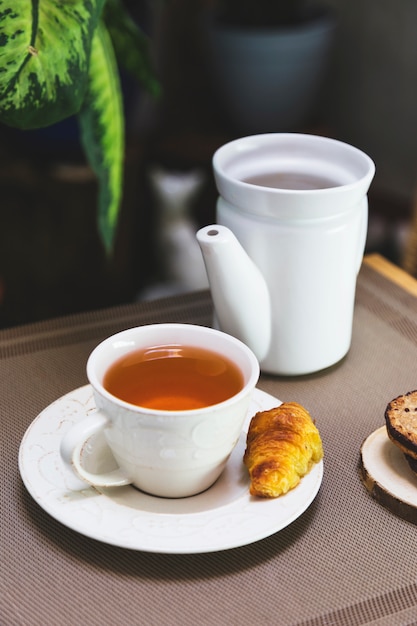 Cup of tea with teapot and breakfast elements