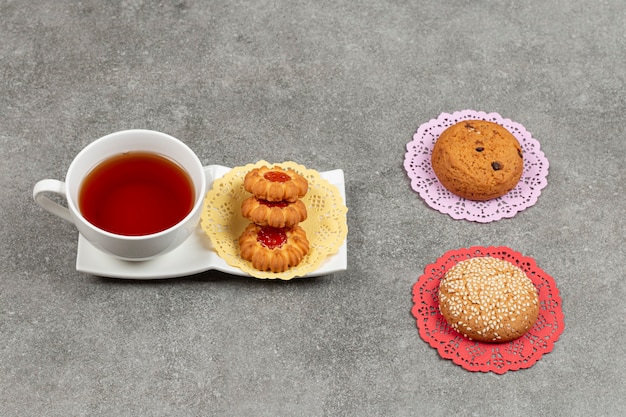 Free photo cup of tea with various biscuits on marble surface