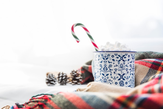 Cup with marshmallow and lollipop near scarf and snags