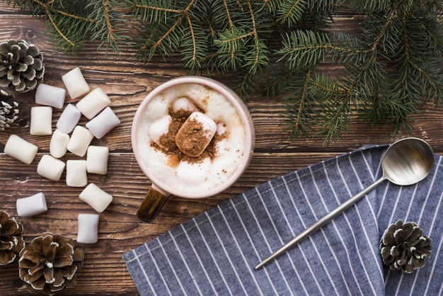 Free photo cup with marshmallows near spoon, fir twigs and snags