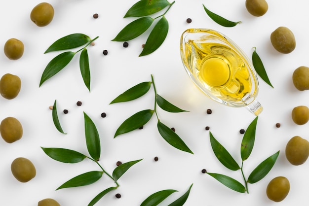 Free photo cup with olive oil surrounded by leaves and olives