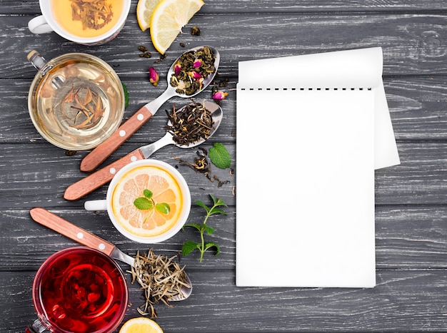 Cup with tea and herbs beside and notebook