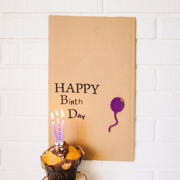 Free Photo cupcake with candles near cardboard with greeting