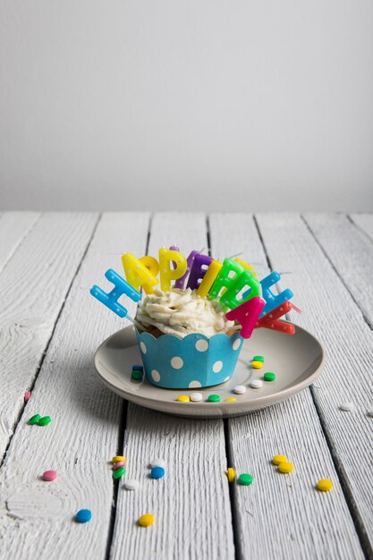 Free photo cupcake with colorful birthday candles and candies on wooden textured table