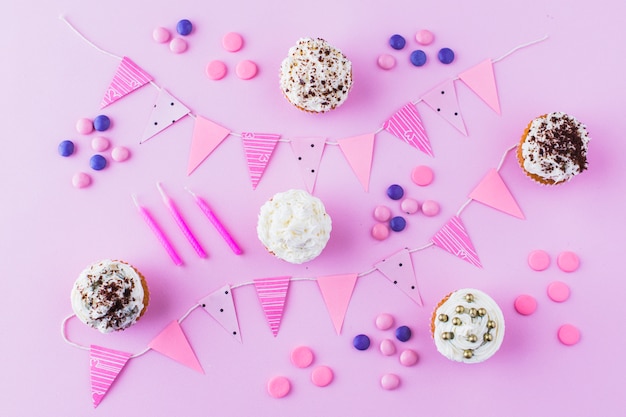 Cupcakes; candies; candles and bunting on pink backdrop