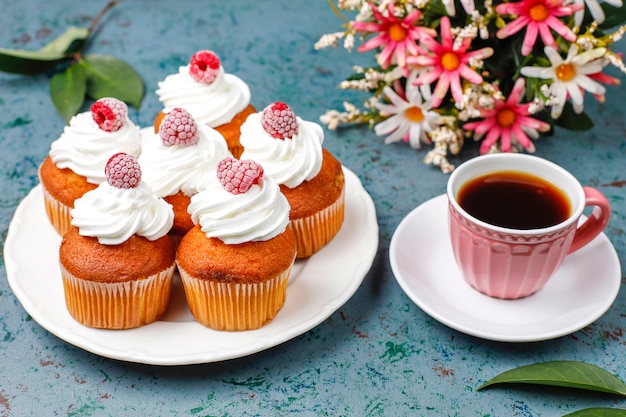 Cupcakes decorated whipped cream and frozen raspberries.