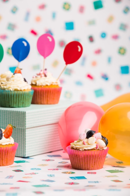 Free photo cupcakes with balloons on table