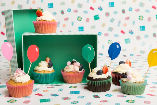 Cupcakes with bright balloon toppings on table