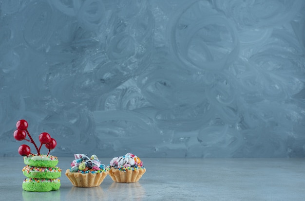 Cupcakes with candy fillings and small donuts on marble background. High quality photo