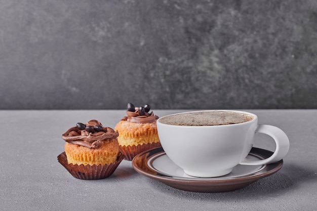 Cupcakes with chocolate cream served with a cup of coffee.