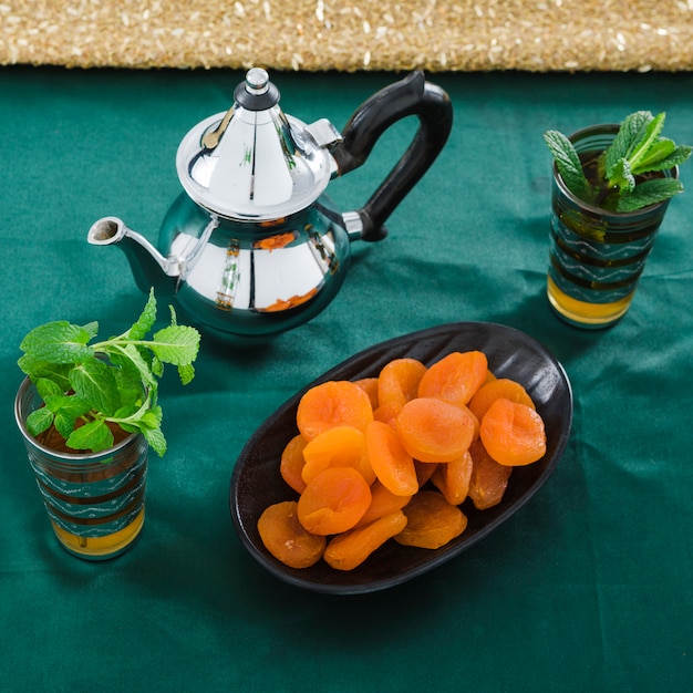 Free Photo cups of drink near teapot and dried apricots 