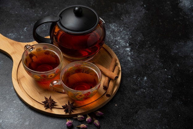 Cups of herbal tea with spices on the wooden board.