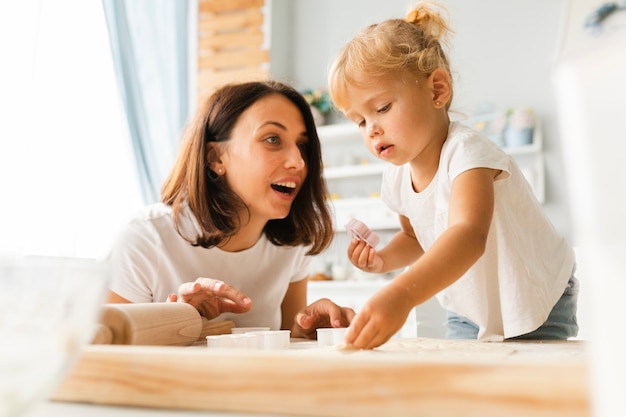 Curious daughter and happy mother preparing cookies