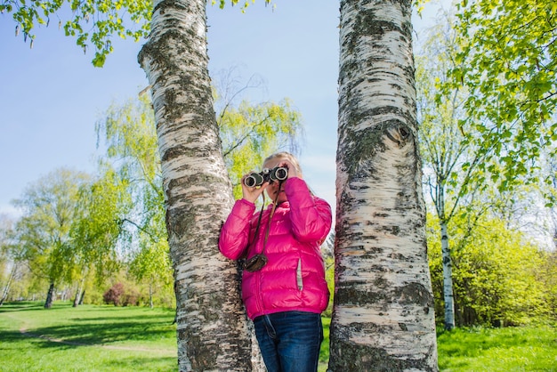 Curious girl with binoculars in the park