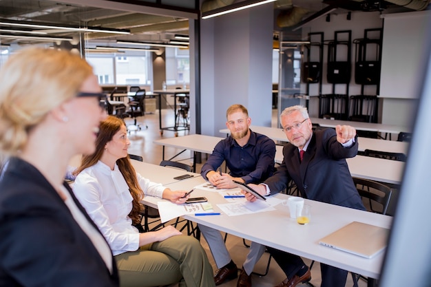 Free Photo curious mature businessman pointing finger at flip chart in presentation