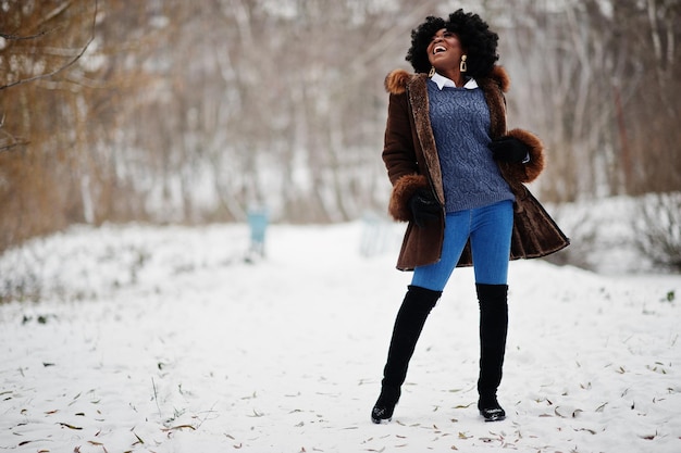 Curly hair african american woman wear on sheepskin coat and gloves posed at winter day