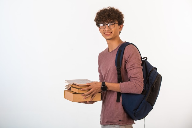 Curly hair boy in optique glasses holding school books and smiling.