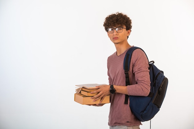 Curly hair boy in optique glasses holding school books.