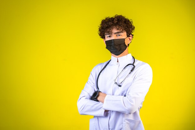 Curly hair boy in white medical uniform with stethoscope wearing face mask