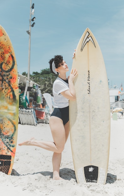 Curly hair woman holding a surfboard in the beach of Rio de Janeiro 