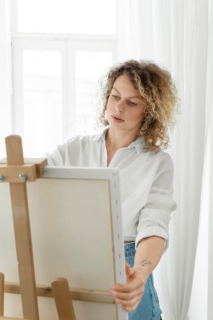 Free photo curly-haired blonde woman painting at home