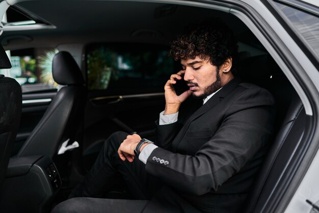 Curly-haired businessman in the backseat talking on the phone