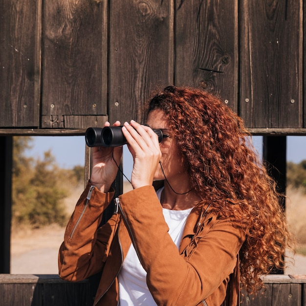 Free photo curly redhead woman watching through binoculars