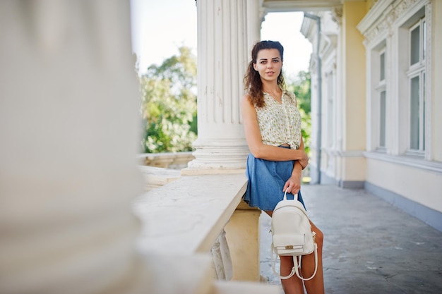 Curly stylish girl wear on blue jeans skirt blouse posed near old vintage house