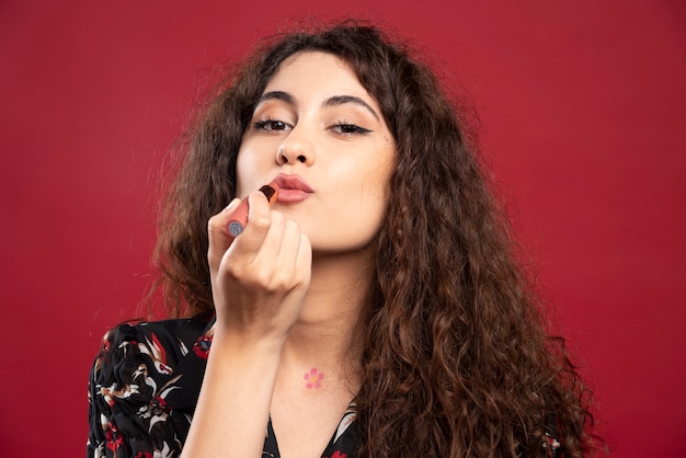 Free photo curly woman applying lipstick.