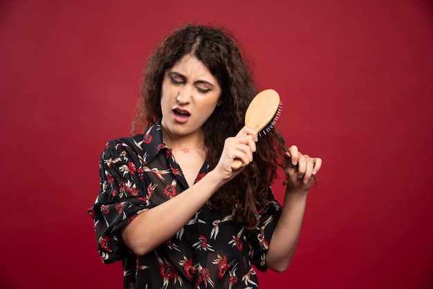 Curly woman combing her hair.