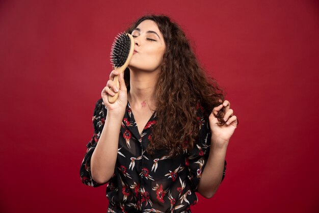 Curly woman kissing comb.