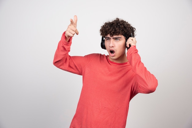 Free Photo curly young man listening to song and singing.