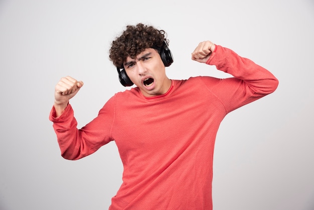 Curly young man listening to song and singing.