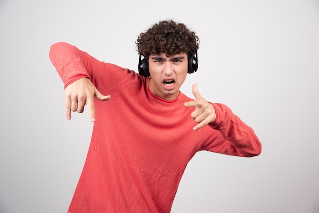 Curly young man with headphones listening to metal.